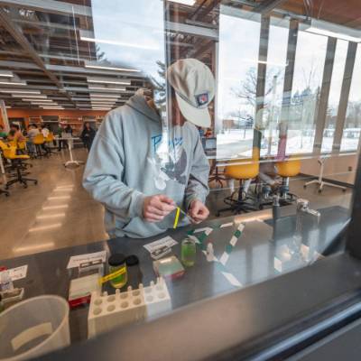 View through a glass window of a student preparing a microscope slide